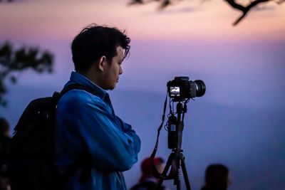 Man photographing against sky during sunset