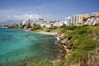Buildings by sea against sky in city