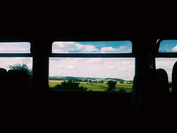 Silhouette trees on field seen through window