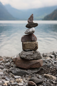 Stack of stones in sea against sky on sunny day