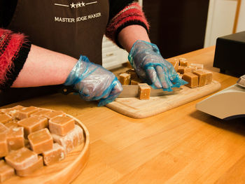 Midsection of person cutting dessert on table