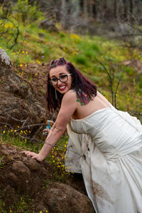Portrait of smiling young woman standing against tree