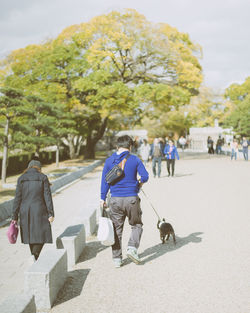 Rear view of people walking on road in city