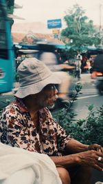 Side view of woman sitting on street in city