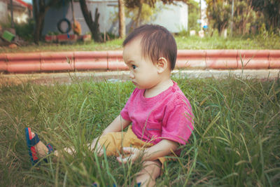 Cute baby sitting on the grass in the garden