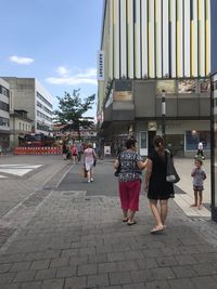 People walking on footpath against buildings in city
