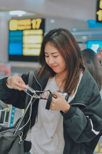 Portrait of smiling young woman using smart phone at airport