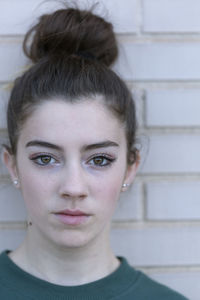 Close-up portrait of young woman against wall
