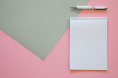 High angle view of pen and book over pink background