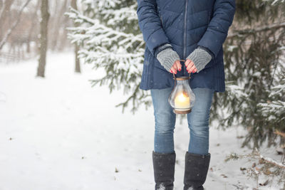 Low section of person standing by frozen tree