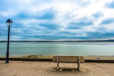 Empty chairs on beach against sky