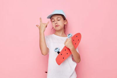 Portrait of cute girl holding gift box against pink background