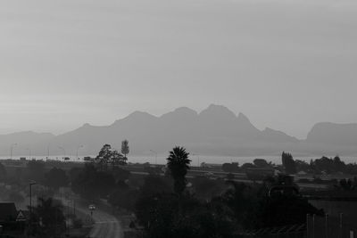 Silhouette trees and buildings against sky at dusk