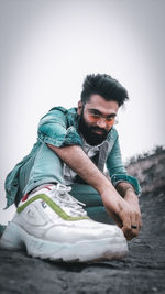 Portrait of young man sitting against clear sky