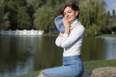 Portrait of young woman standing against lake