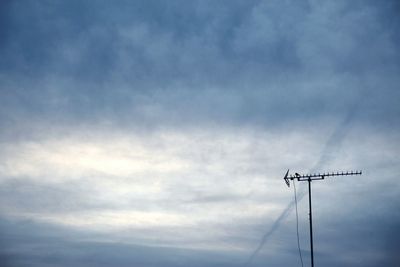 Low angle view of silhouette communications tower against sky