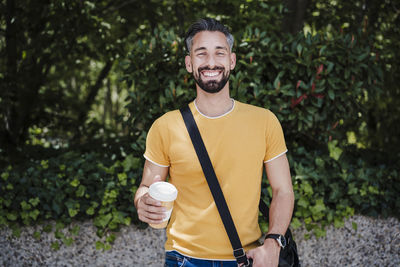 Portrait of smiling young man standing against plants