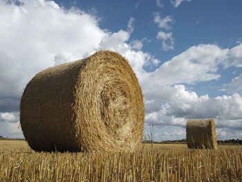 Hay bales on field against sky