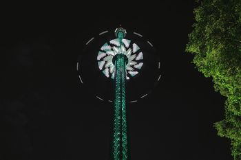 Low angle view of illuminated chain swing ride at prater during night