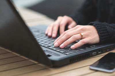 Cropped hands using laptop at table