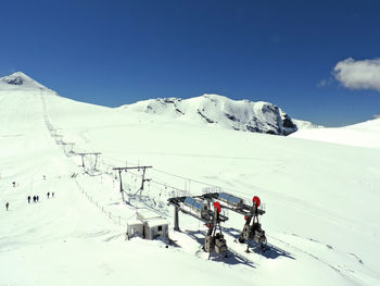 View of snowcapped mountain range against sky, above stelvio pass and with a ski-lift on foreground.