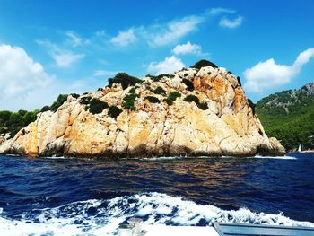 Rock formations by sea against blue sky