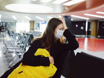 Young woman sitting on seat at airport