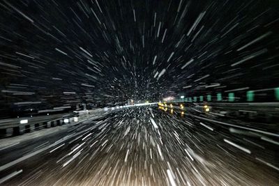 Light trails on road against sky at night