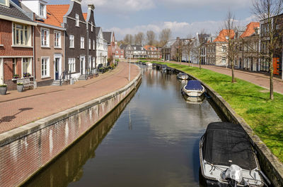 Canal in a new neighbourhood, with sloops and canal houses, brick quay and grassy slope