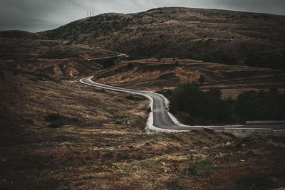 Scenic view of road by mountain against sky