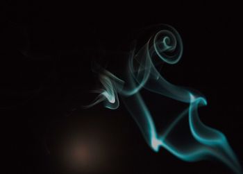 Close-up of illuminated smoke over black background