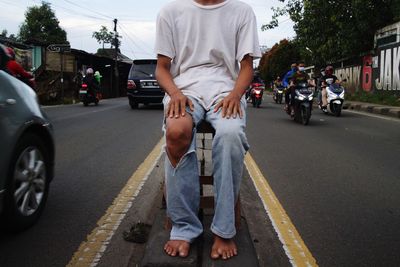 Low section of man walking on road in city