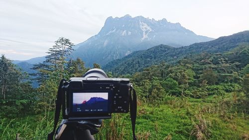 Man photographing camera on mountain against sky