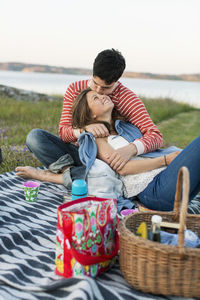 Man kissing girlfriend during picnic on field