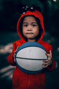 Portrait of cute boy holding ball while standing outdoors