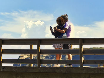 Low section of woman standing on railing against sky