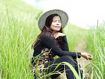 Young woman looking away while sitting on land