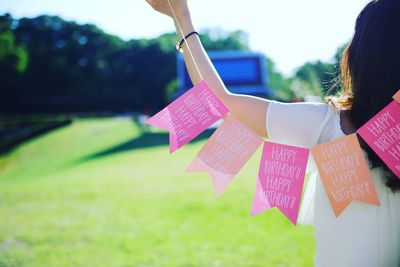 Close-up of woman with umbrella hanging on grass against sky