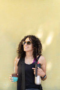 Mixed race woman smiling while drinking mate outdoors.