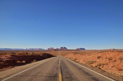Road amidst desert against clear sky