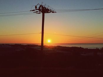 Silhouette electricity pylon against sky during sunset