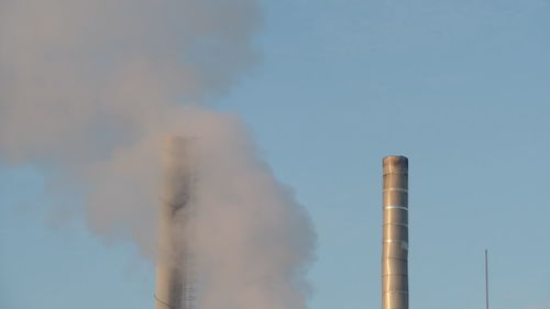 Low angle view of smoke emitting from chimney against sky