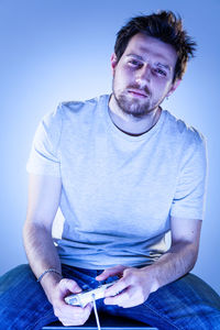 Portrait of man sitting on table against blue background