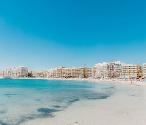 Sea and buildings against clear blue sky