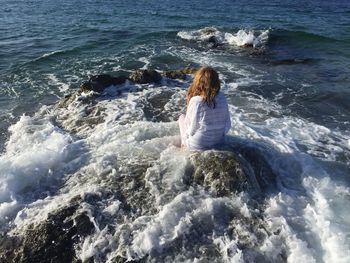 Rear view of young woman sitting at beach