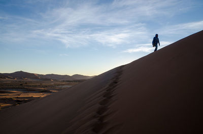 Low angle view of woman walking on sand dune at desert