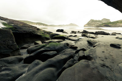 Scenic view of rocks on beach against sky