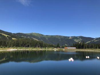 Scenic view of lake and mountains against clear blue sky