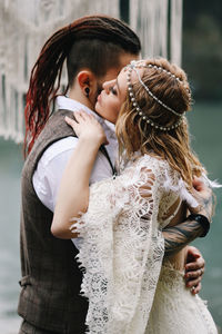 A loving married couple the bride and groom in suits celebrate wedding near the mountains and water