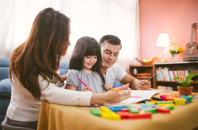 Parents teaching daughter in living room